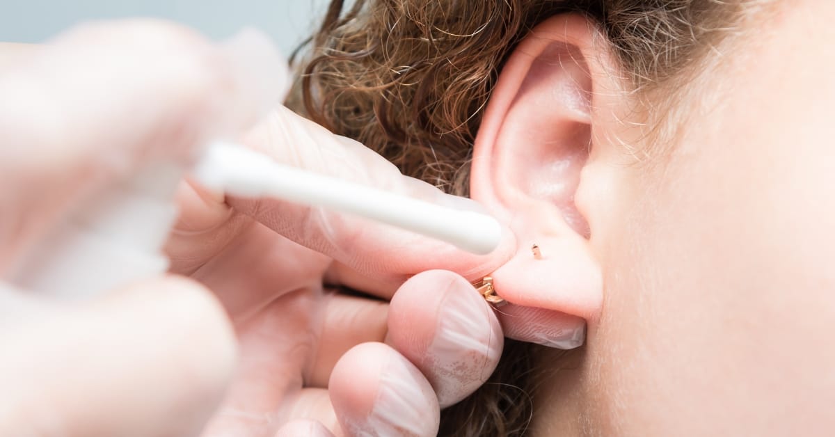 Technician cleans a fresh ear piercing at Express Med Spa, showing how to clean ear piercing properly.