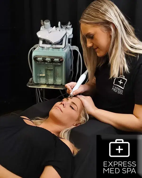 Provider in an Express Med Spa shirt guiding a hydrafacial wand across a patient's forehead beside the hydrafacial device at the Frankfort, IL clinic.
